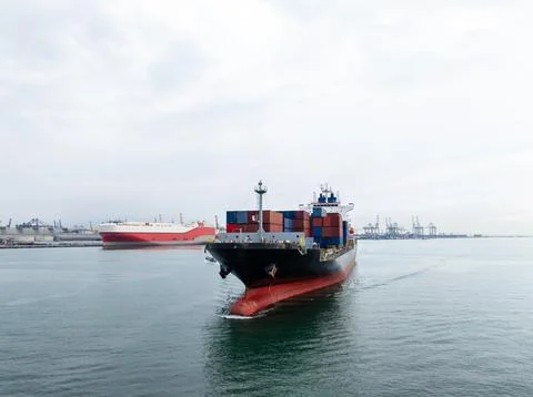 Large Container Ship Maneuvering Through Busy Harbor Channel Wide Shot Stock Photos