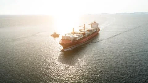 Large Container Ship Maneuvering Through Open Sea During Golden Hour Wide Sho Foto stock