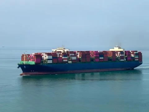 Large Container Ship Navigating Across Open Blue Ocean Waters Wide Shot 库存照片