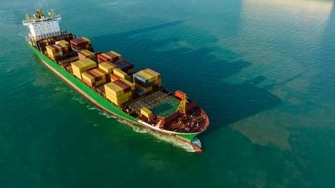 Large Container Ship Navigating Coastal Waters During Sunset High Angle Shot Stock Photos