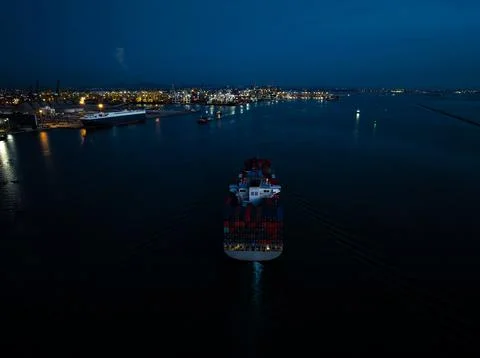 Large Container Ship Navigating Harbor Entrance At Twilight In Si Racha Cho.. Foto stock