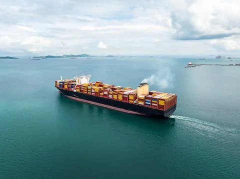 Large Container Ship Navigating Open Ocean Toward Harbor Under Cloudy Sky H.. Foto stock
