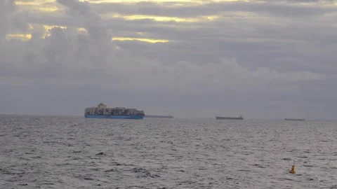 A large container ship sails across a calm blue ocean at sunset. Stock Footage 319211484