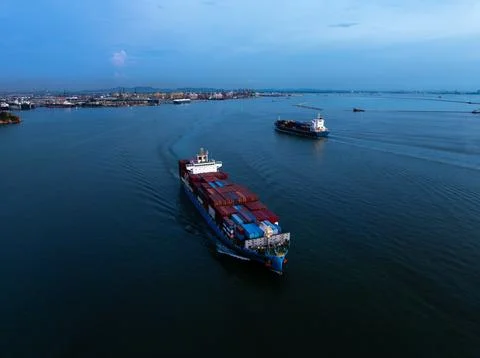 Large Container Ships Navigating Calm Waters Near Industrial Port Facilitie.. Stock Photos