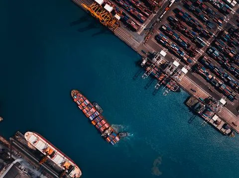 Large Container Vessel Navigating Through Busy Industrial Port Terminal Wid.. Stock Photos