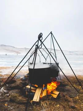A large cooking pot is positioned over a campfire, simmering away Stock Photos
