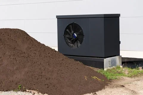 Large cooling unit next to a pile of soil outdoors at a facility Stock Photos