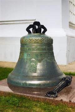 Large copper bell on ground nea temple wall Stock Photos
