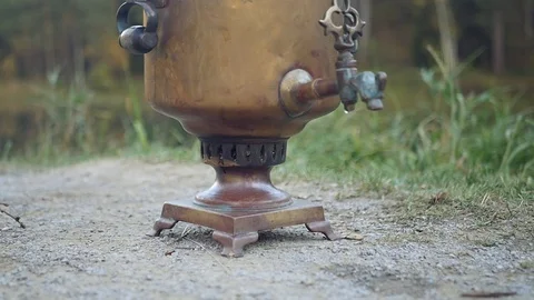 A large copper samovar stands in the forest by the lake and smokes. 1920x1080 Stock Footage 105858567
