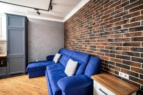 Large corner blue sofa on the background of decorative red brick in the inter Stock Photos
