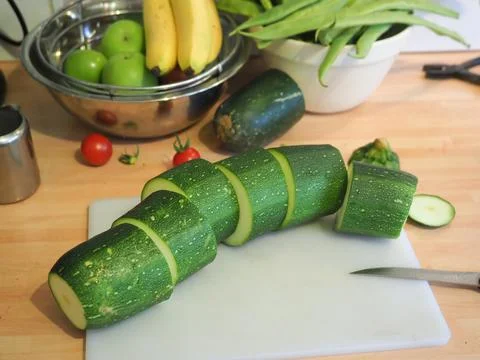 A large courgette chopped into sections on kitchen work surface Stock Photos