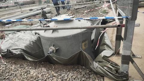A large, covered container at a construction site, secured with fencing and.. Stock Photos