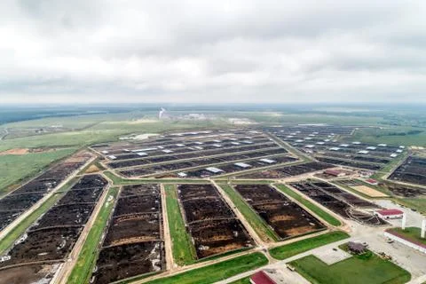 Large cowshed in the middle of green fields. Lots of stockyards where cows graze Stock Photos