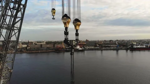 Large crane and hooks with a cargo port in the background. Multi-ton crane hooks Video stock 154351439