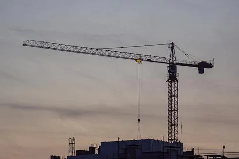 A large crane at a construction site undergoing dusk, against a gradient of.. Foto stock