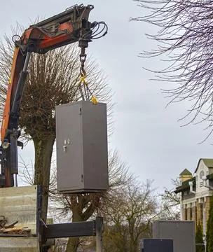 A large crane is lifting a storage unit from a truck in a neighborhood with b Stock-Fotos