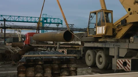 A large crane loads a huge pipe into a truck body at a metallurgical plant. 4K Stock Footage 133768764