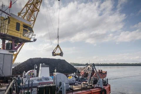 Large cranes are engaged in loading coal from a ship onto the dock. The port Stock Photos