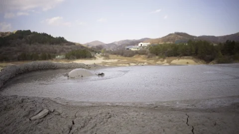 Large crater of bubbling mud volcano releasing gases on a spring sunny day Stock Footage 105176089