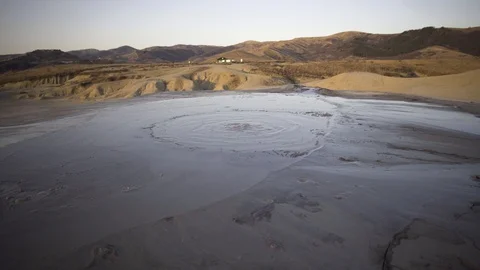 Large crater of bubbling mud volcano releasing gases in an arid landscape Stock Footage 105176496