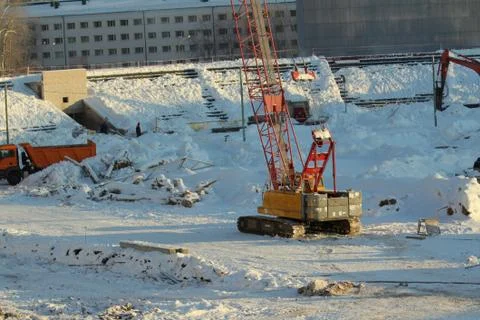 Large crawler crane works at a construction site on a frosty sunny day in win Stock Photos