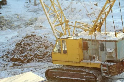 Large crawler crane works at a construction site on a frosty sunny day in win Stock Photos