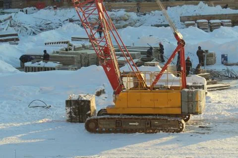 Large crawler crane works at a construction site on a frosty sunny day in win Stock Photos