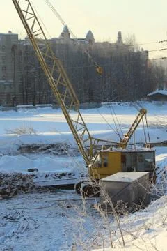 Large crawler crane works at a construction site on a frosty sunny day in win Stock Photos