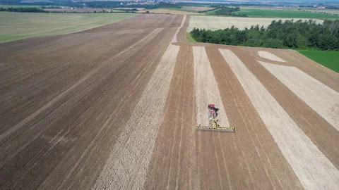 A large crawler tractor in a field with a harrow loosens the soil. Modern Stock Footage 161855698