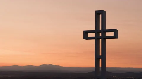 Large cross silhouette rises over the horizon with a colorful cloudy sky. Stock Footage 147293447