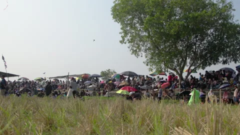 Large crowd gathered under umbrellas at an outdoor festival on a sunny day Stock Footage 340621823