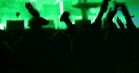 Large crowd in green light silhouette of clapping hands at music festival stage Stock Footage 130482537