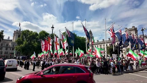 Large crowd of Iranian protesters wave green white red flags in a busy London Stock Footage 338011984