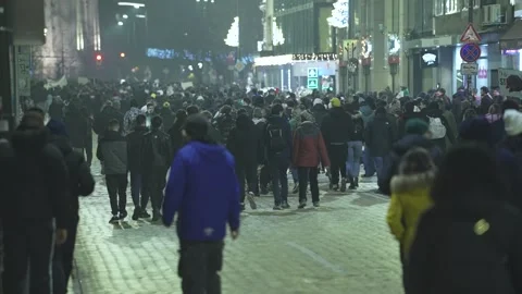 A large crowd moves along a paved boulevard in nighttime Sofia 스톡 동영상 324556489