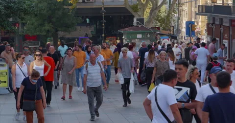 A large crowd of people calmly walking on a clear sunny warm day along a crowded Stock Footage 232121852