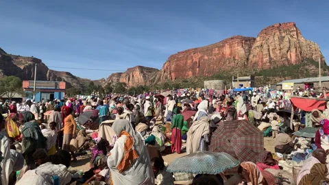 Large crowd of people gathering at a traditional outdoor market in a rural Stock Footage 345944035