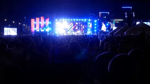 A large crowd of people at an open air concert in front of the stage in the Stock Footage 114986901