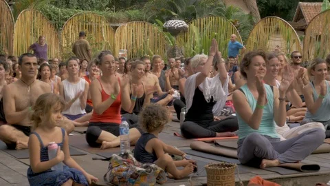 Large crowd of people sitting cross legged on yoga mats and clapping Stock Footage 110733028