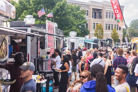 Large crowd of people wait in line at food trucks Stock Photos