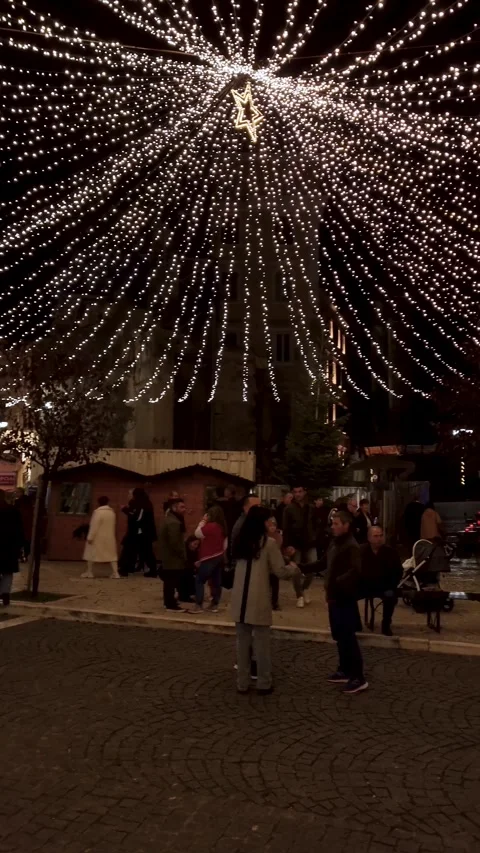 Large crowd of people walking in a city public square beautifully decorated Stock Footage 332583700
