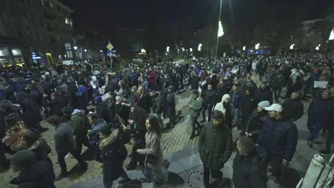 A large crowd of protesters moves along a yellow cobblestone boulevard in Sofia 스톡 동영상 324556691