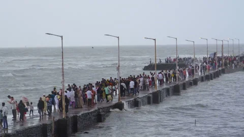 A large crowd walks along the narrow stone causeway of the Haji Ali Dargah Stock Footage 340036347