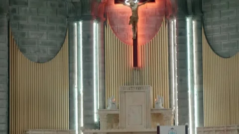 A large crucifix with a statue of Jesus Christ mounted on an altar wall  Stock Footage 340624706