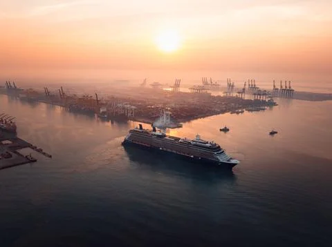 Large Cruise Ship Navigating Through Busy Industrial Port During Golden Sun.. Stock Photos