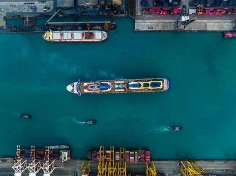 Large Cruise Ship Navigating Through Industrial Shipping Port Terminal Wide.. Photos
