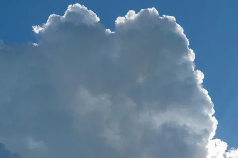 Large cumulus cloud with bright silver lining against deep blue sky, close .. Stock Photos