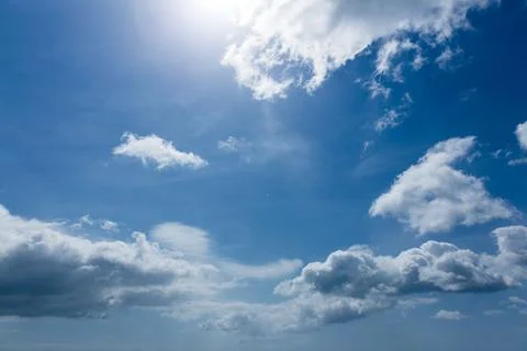 Large cumulus clouds are floating across flat design sky with sunlit highlights Stock Photos