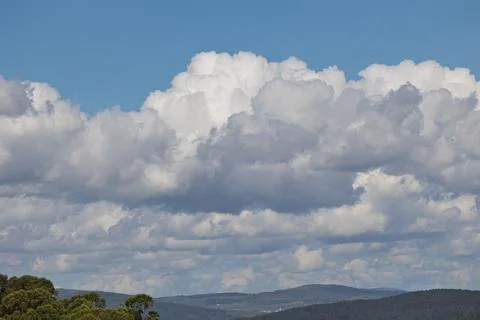 Large cumulus clouds forming over green hills and forest Stock Photos