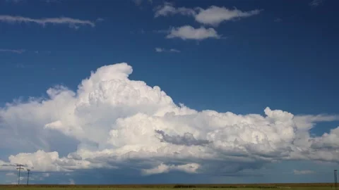 Large Cumulus Clouds Over Agricultural Field Under Clear Blue Sky Stock Footage 342239829