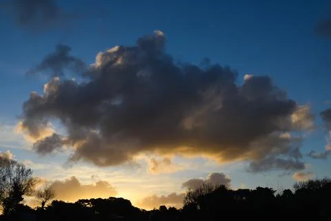 Large cumulus isolated and centered on the horizon at sunrise Stock Photos